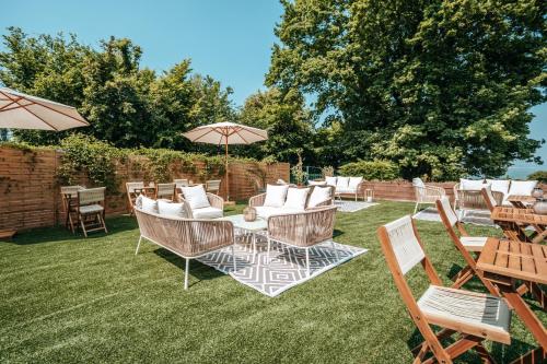 un patio con sillas, mesas y sombrilla en Hôtel Le Romantica en Pennedepie