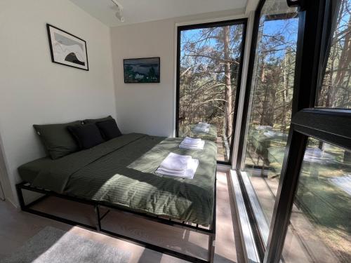 a bedroom with a bed and a large window at Treehouse Virš Bedugnės in Jurbarkas