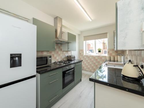 a kitchen with green cabinets and a stove top oven at 2BDR Peaceful Ground Floor Apartment Free Parking - Pass the Keys in Wokingham