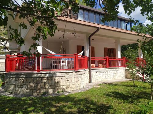 una casa con un portico rosso e un muro di pietra di Casa BnB Pappappero Monti della Laga a Fioli