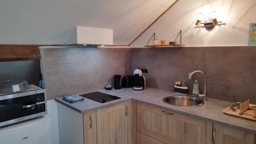 a small kitchen with a sink and a microwave at Le Wilson - accès Paris facile ! in Limeil-Brévannes