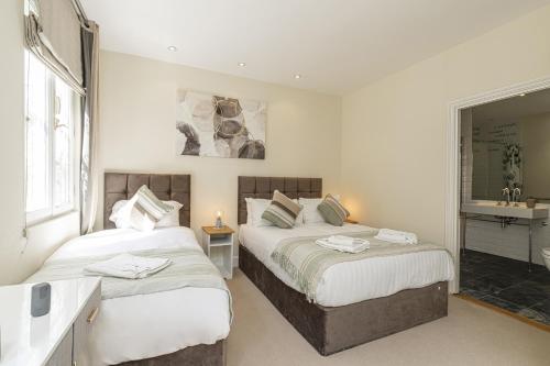 a bedroom with two beds and a bathroom with a sink at Fabulous House near the Science Museum in London
