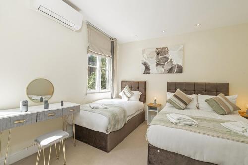 a bedroom with two beds and a desk and a mirror at Fabulous House near the Science Museum in London
