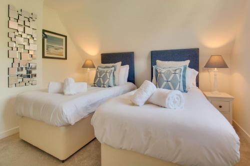 a bedroom with two beds with white and blue pillows at Cobblers Cottage, Wells Next The Sea in Wells next the Sea
