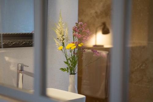 un jarrón de flores sentado en la parte superior de un fregadero en Les Canisses, magnifique appartement avec terrasse au cœur d'Uzès, en Uzès