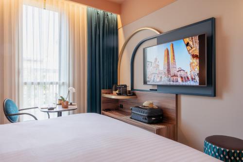 a hotel room with a bed and a flat screen tv at Mercure Bologna Centro in Bologna