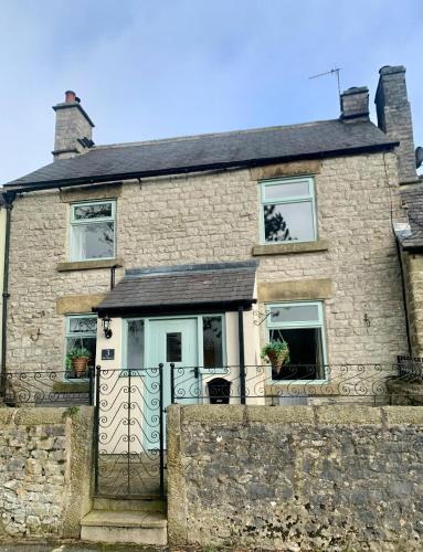 a stone house with a gate in front of it at The Beautiful Bobbin - Premium Cottage with views, local walks, wood burner & pubs in Tideswell