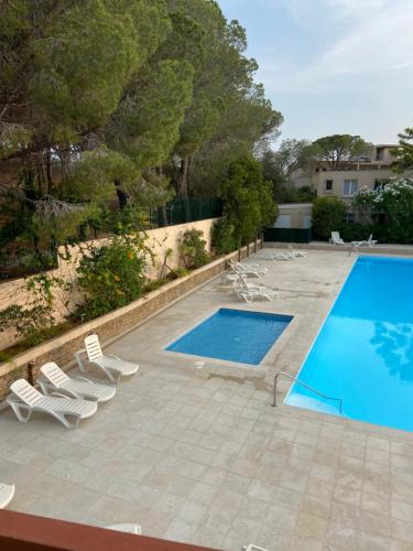 une piscine avec des chaises longues et une piscine dans l'établissement Cotépiscine, au Lavandou