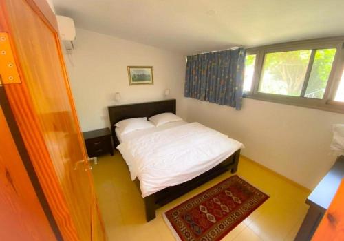 um quarto com uma cama com lençóis brancos e uma janela em לבנון בחד נס LAVNUN BEHAD NES em Had Nes