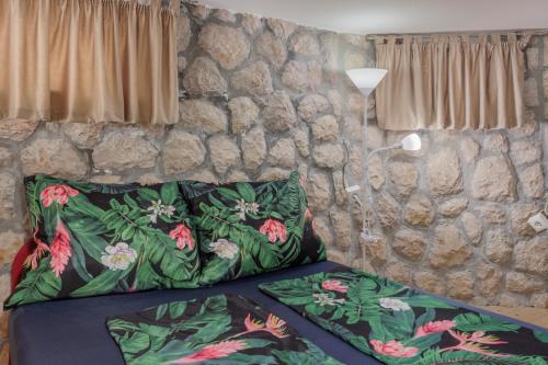 - un lit avec deux oreillers et un mur en pierre dans l'établissement Apartments TOMMI, à Dramalj
