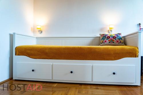 a white bed with an orange blanket on top of it at STÉG64 - Ráckeve - hostAID in Ráckeve