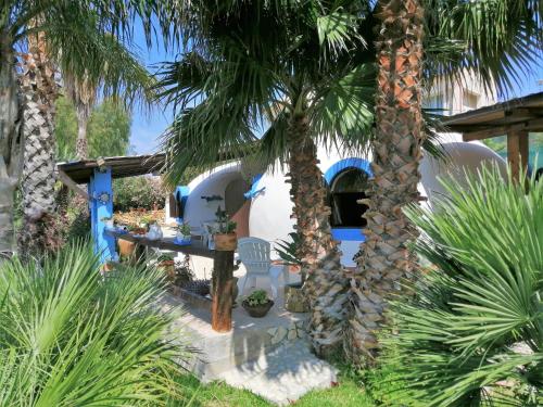 a garden with palm trees in front of a house at Oasi Sul Mare - Bungalow a 120m dalla spiaggia in Sciacca