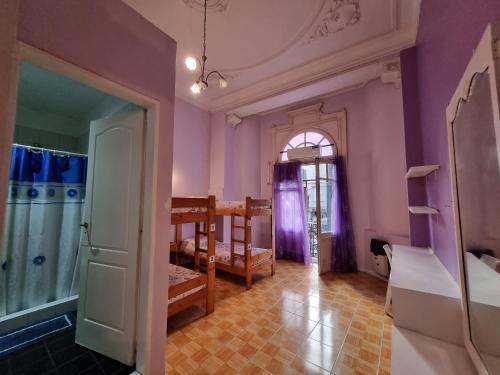 Habitación con paredes moradas, cama y ventana en Hostel Estoril en Buenos Aires