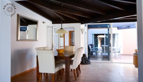a dining room with a wooden table and white chairs at Villa Privilege Sun in Corralejo