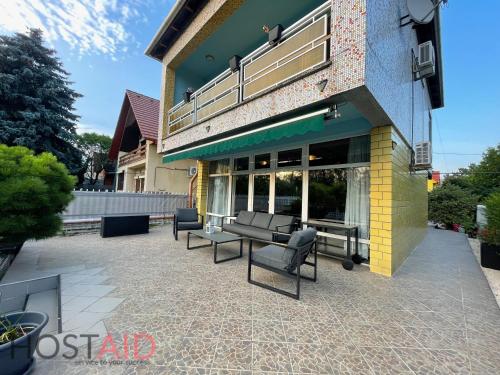 a patio with chairs and tables in front of a building at STÉG64 - Ráckeve - hostAID in Ráckeve