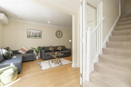 a living room with a couch and a staircase at Fabulous House near the Science Museum in London
