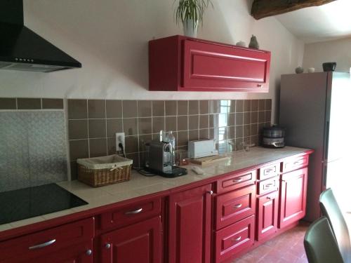 a kitchen with red cabinets and a black refrigerator at Duplex Cosy Vue Colline in Cavaillon