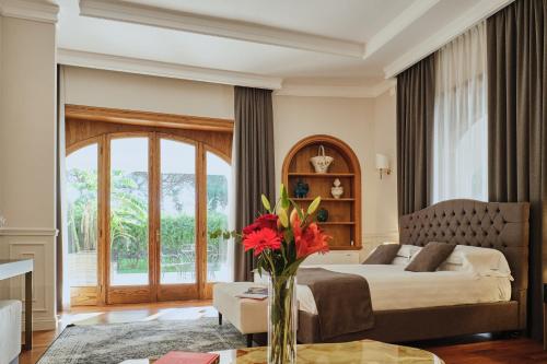 1 dormitorio con 1 cama y un jarrón de flores sobre una mesa en Villa Lena Puglia, en Oria