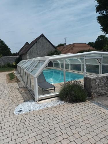 a glass house with a swimming pool and a chair at La Maison de Zoé in Saint-Denis-sur-Loire