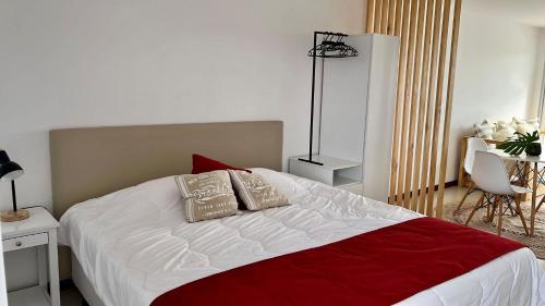a bedroom with a large bed with a red and white blanket at Monoambiente 509, Dos Orillas in Colonia del Sacramento