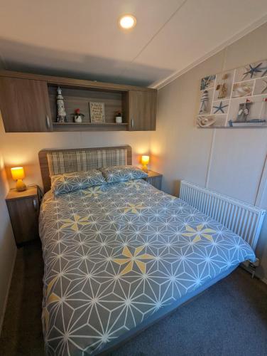 a bedroom with a bed with a blue and yellow bedspread at Panoramic Views Relaxing Caravan Littlesea Haven Weymouth in Weymouth