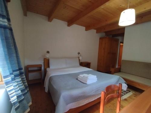a bedroom with a white bed and a chair at Villa Gjeçaj Guesthouse and Restaurant in Theth