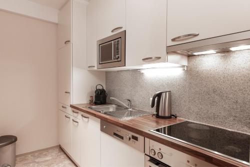 a kitchen with white cabinets and a sink at Panorama Appartements in Längenfeld