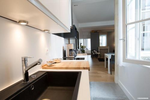 une cuisine avec un évier et une grande fenêtre dans l'établissement L'Appartement : location les merciers., à La Rochelle