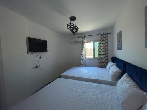 a small bedroom with two beds and a tv at Sun Mirror Chalet El Sokhna in Ain Sokhna