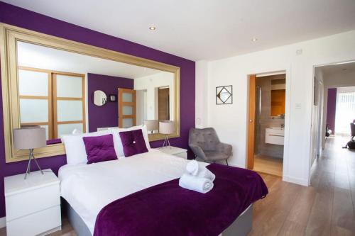 a bedroom with a large bed with purple walls at Mosspark Boulevard Exec Apartment ii - Free Parking in Glasgow