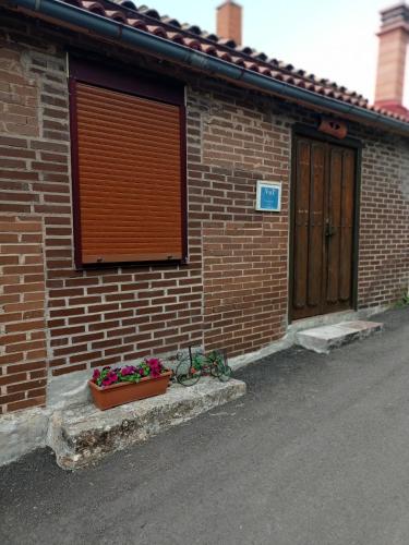 a brick building with a door and a flower pot at Casa Manuel y Ana María. in Llombera