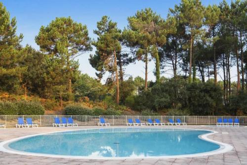 - une piscine avec des chaises et des arbres bleus dans l'établissement Petite Villa La Pantoufle au Domaine du Golf de Pinsolle, à Soustons