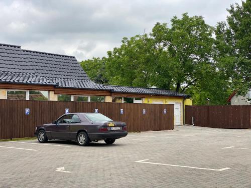 a car parked in a parking lot next to a fence at Blueline Motel in Jászberény