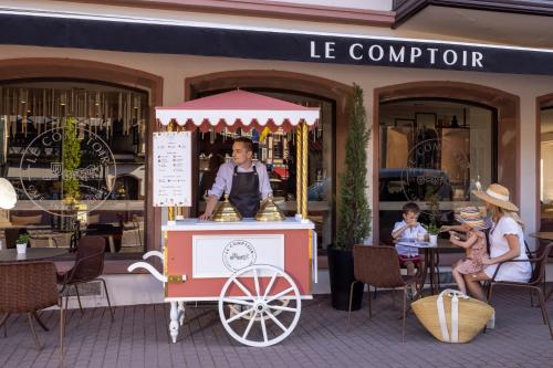 a man in a food cart in front of a store at Hotel La Diligence in Obernai