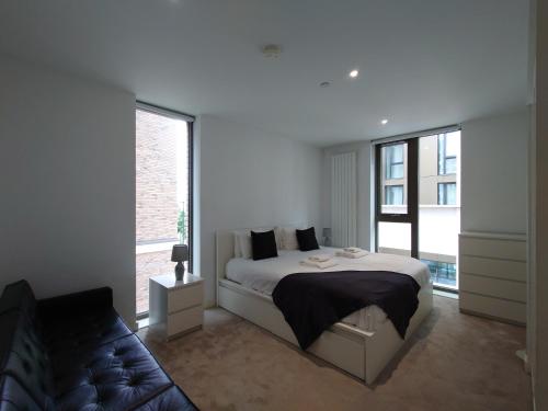 a white bedroom with a bed and a large window at Fully Serviced One Bed Apartment in Royal Wharf in London