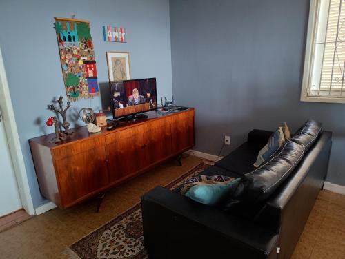 a living room with a leather couch and a wooden cabinet at Praia Seca, 10 pessoas, em frente à lagoa do Tomé in Araruama