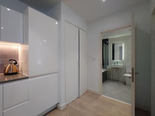 a bathroom with white cabinets and a toilet at Fully Serviced One Bed Apartment in Royal Wharf in London