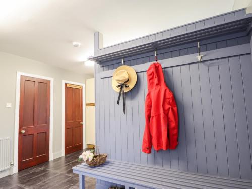 une veste rouge et un chapeau suspendu sur un mur dans l'établissement Challenger Lodge, à Lairg