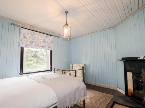 a bedroom with blue walls and a bed and a window at Challenger Bothy in Lairg