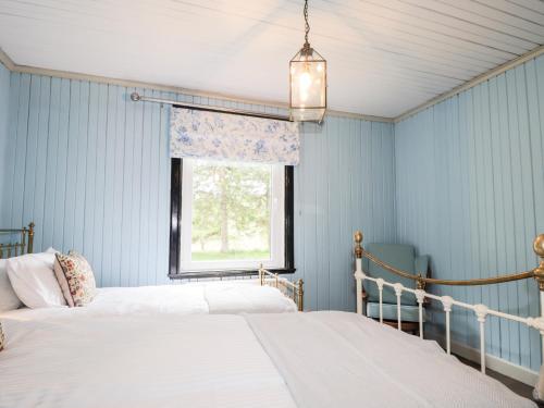 two beds in a blue bedroom with a window at Challenger Bothy in Lairg