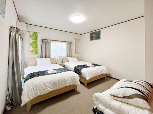 a bedroom with three beds and a window at Kanazawa Seiren Le Lotus Bleu in Kanazawa