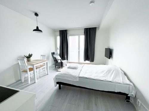 een witte slaapkamer met een bed en een tafel en stoelen bij Kotimaailma Oulu Apartments Kasarmintie in Oulu