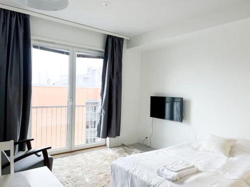een slaapkamer met een bed, een tv en een raam bij Kotimaailma Oulu Apartments Kasarmintie in Oulu