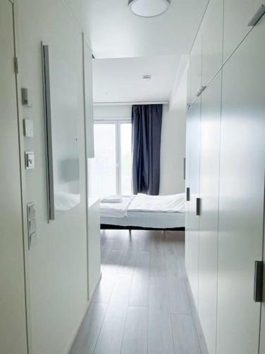 een witte kamer met een bed en een raam bij Kotimaailma Oulu Apartments Kasarmintie in Oulu