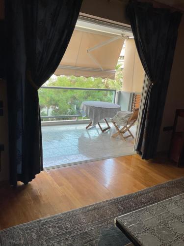 Blick auf ein Wohnzimmer mit einem Tisch und einem Fenster in der Unterkunft Luxury apartment in the elite area in Athen