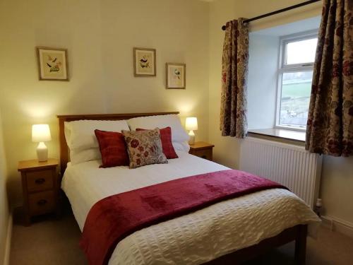 Un dormitorio con una cama con almohadas rojas y una ventana en The Beautiful Bobbin - Premium Place to stay - Cottage with views, local walks & pubs, en Tideswell