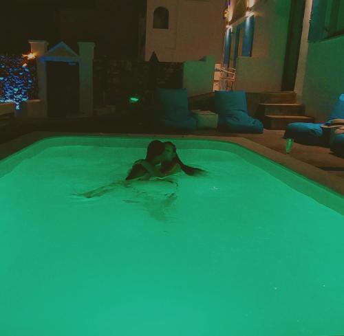 a woman laying in a swimming pool at night at TINOS AQUA PALAZZO in Tinos Town