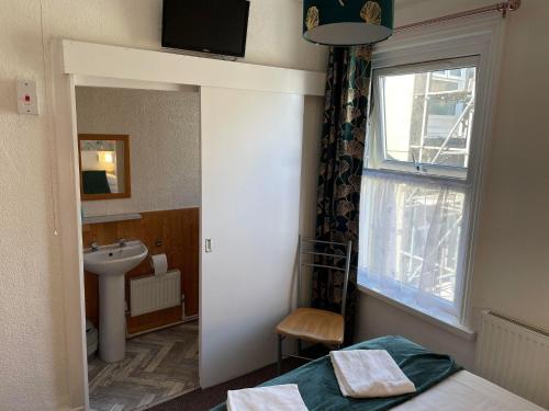 łazienka z łóżkiem, umywalką i oknem w obiekcie Cleveland Court Apartments w Blackpool