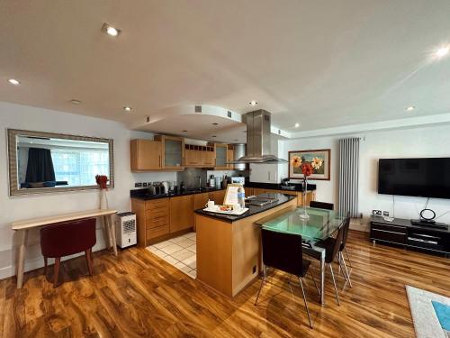 a large kitchen with a glass table and a television at Canary Wharf - Luxury Apartments in London