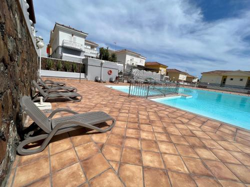 eine Reihe von Liegestühlen neben einem Pool in der Unterkunft "Flora B&B "- Rooms in Privat Home in Maspalomas